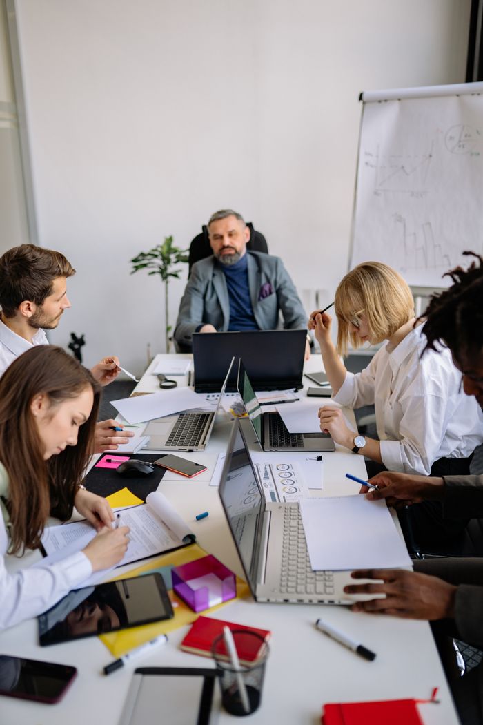 About Group of colleagues brainstorming and planning in a modern office with laptops and documents.